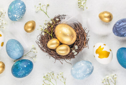 Easter gold and blue eggs in a nest on a white background. Easter background with copy space