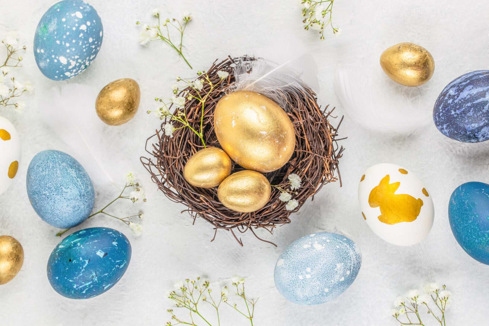 Easter gold and blue eggs in a nest on a white background. Easter background with copy space