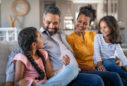 Happy couple with two girls relaxing at home together.