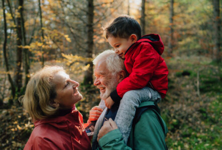 Photo of grandparents and their grandson having a walk through the forest