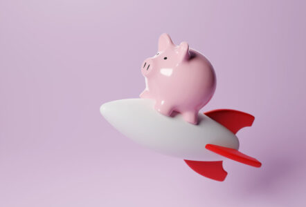 Pink piggy bank on a white toy rocket on pink background. Illustration of the concept of skyrocketing stock prices