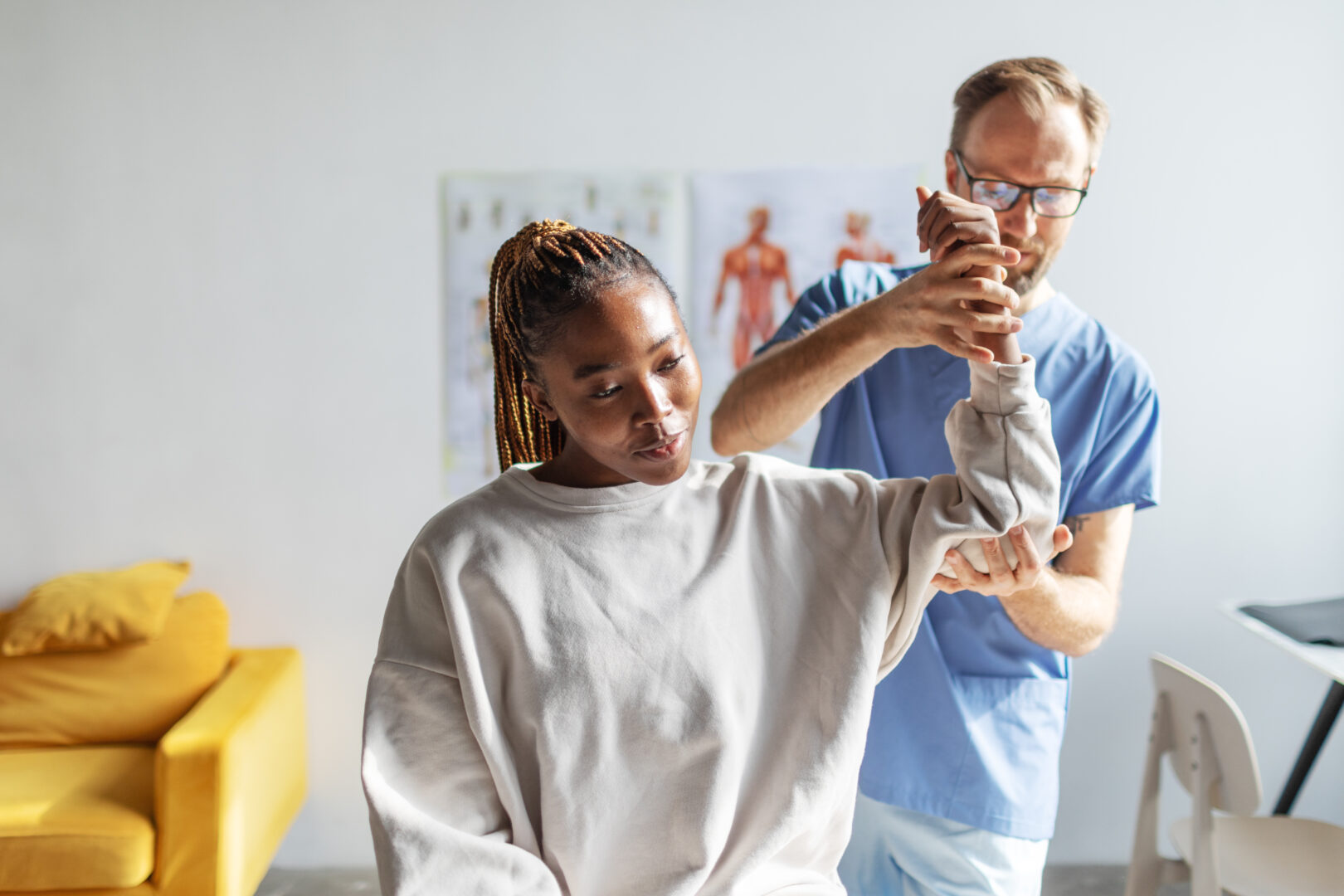 Physical therapist helping young black woman with her shoulders