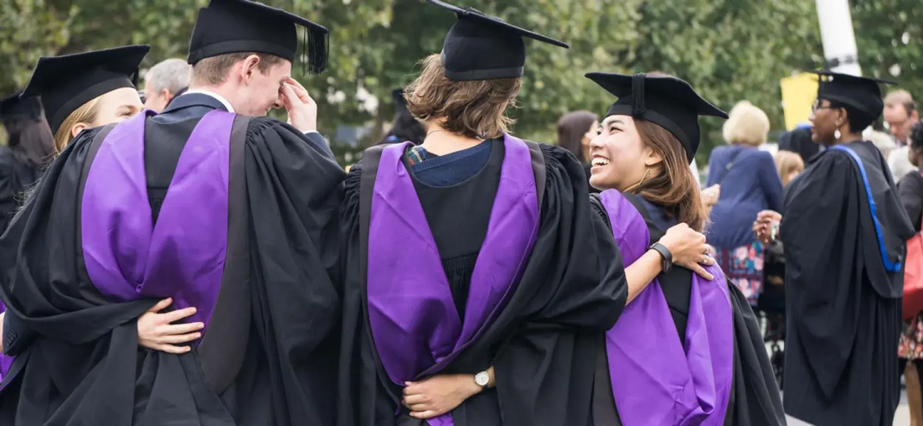 group of graduates with purple sashes huddled together