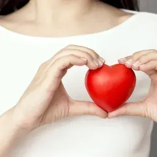 lady in white top holding red heart