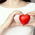 lady in white top holding red heart