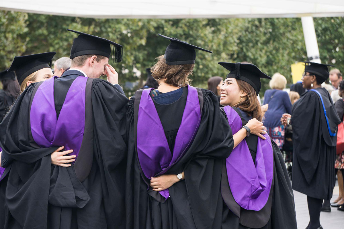 group of graduates with purple sashes huddled together