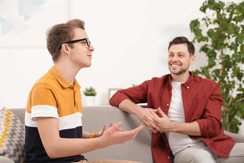 two men chatting on sofa